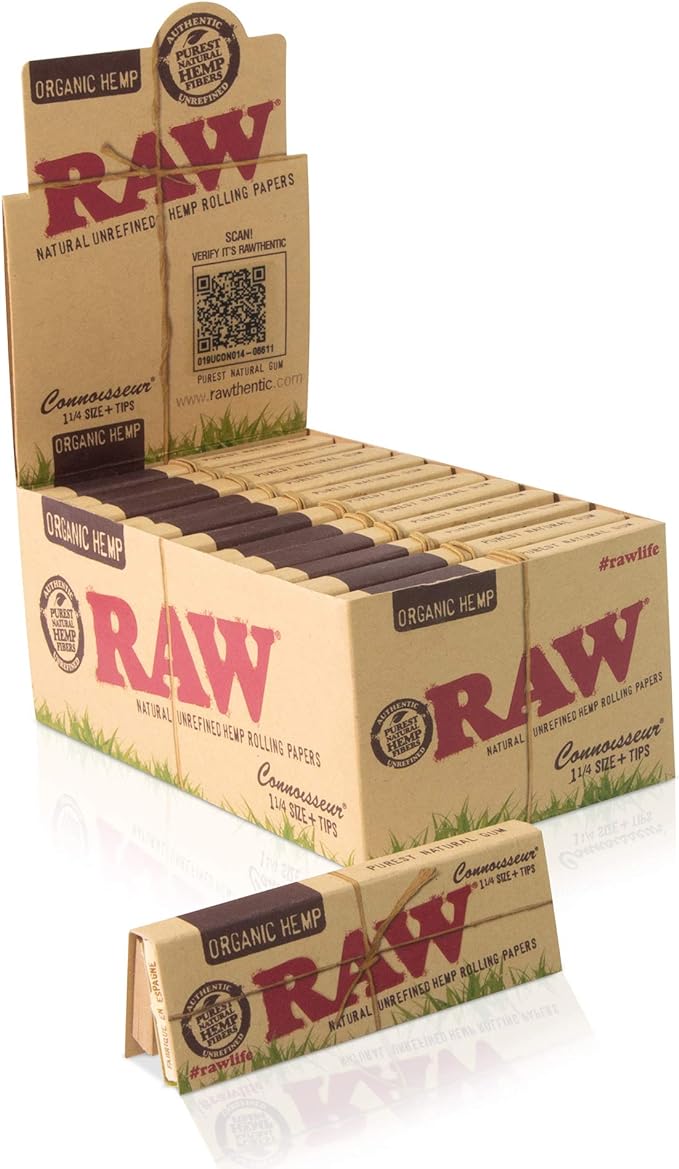 Front angled view of the RAW Connoisseur Organic Hemp 1 1/4 papers and tips 24-count display box in natural light brown with green and red accents. This retail-ready counter display box neatly showcases these convenience-focused rolling kits to boost impulse purchasing at checkouts.