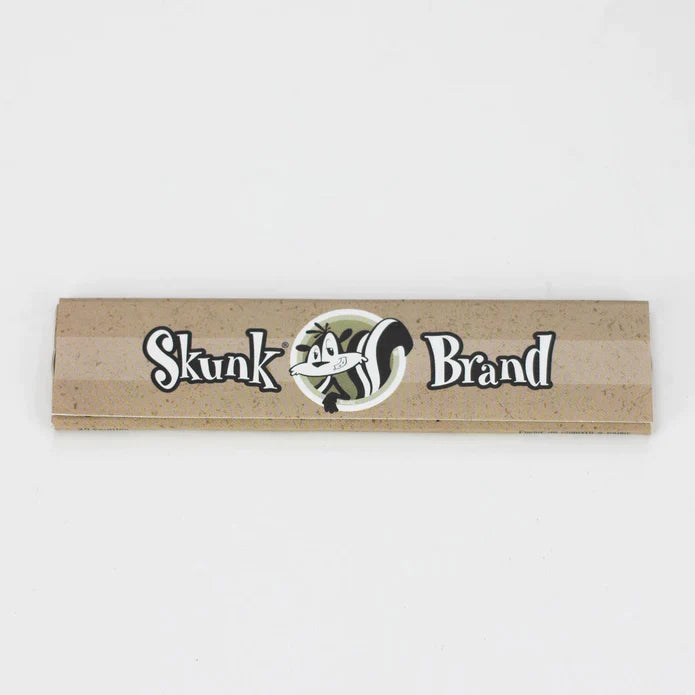 Front profile view of a single Skunk Brand King Size Slim rolling paper booklet showcasing the purple background and black accents. These classic unflavored sheets are made from 100% pure hemp to deliver a clean, smooth, and authentic smoking session.