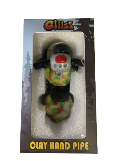 Angled profile view of the 5" Glizzy Clay Hand Pipe with a green accent. This novelty food-themed clay smoking instrument is designed to visually replicate a hot dog, featuring an integrated deep-dish bowl and side-carb.