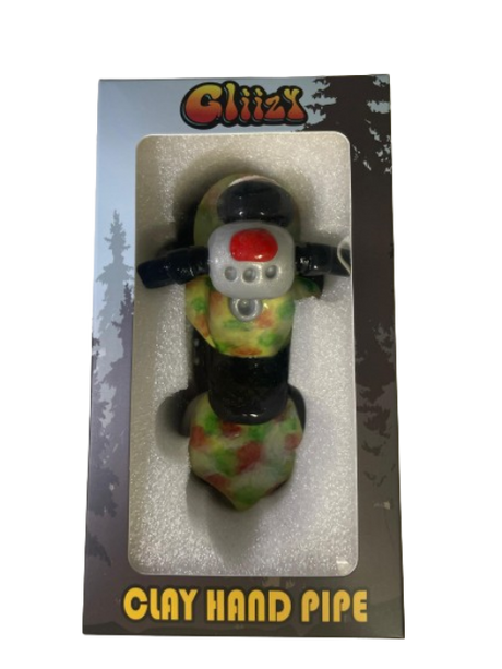Angled profile view of the 5" Glizzy Clay Hand Pipe with a green accent. This novelty food-themed clay smoking instrument is designed to visually replicate a hot dog, featuring an integrated deep-dish bowl and side-carb.