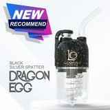 Angled overhead view of the Lookah Dragon Egg Electric Dab E-Rig featuring a black base decorated with grey splatter marks. This capsule-style portable e-rig features a unique bottom-mounted water bubbler and a magnetic cap to deliver cool, smooth, and filtered concentrate hits on the go.