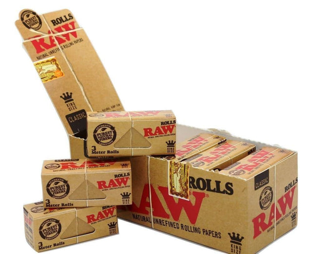Front angled view of the RAW Classic King Size 3-Meter Rolls 12-count display box in natural kraft brown packaging with red branding. This retail-ready carton provides smoke shops with an attractive countertop presentation for these customizable, unbleached rolling papers.
