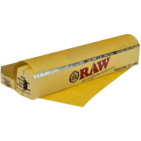 Angled overhead view of the RAW Dual Coated Parchment Paper Roll box in natural brown, shown open with the light brown parchment partially rolled out. The convenient built-in cutting edge allows extractors and dabbers to easily tear off custom lengths of non-stick paper for pressing or portioning.