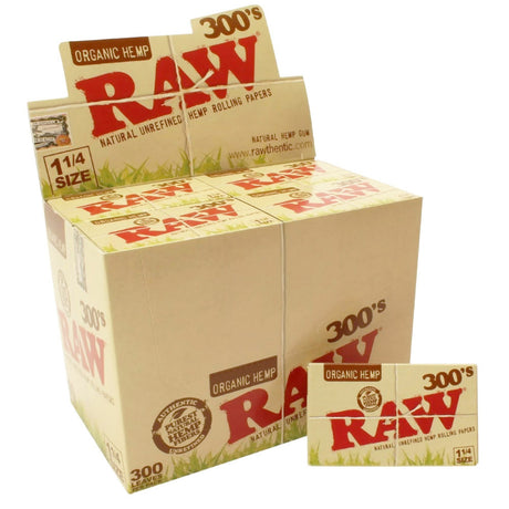 Angled overhead view of the RAW Organic Hemp 300s 1 1/4 retail display box packed with individual booklets in tan and dark green. This bulk wholesale package makes a highly recognizable counter display item for smoke shops and dispensaries.