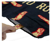 Close-up view of the RAW Stash Pocket Beach Towel in black and red, highlighting the concealed compartment. This 100% cotton large-format fabric features an integrated Velcro-sealed stash pocket to safely conceal smoking hardware and unrefined materials from the elements.