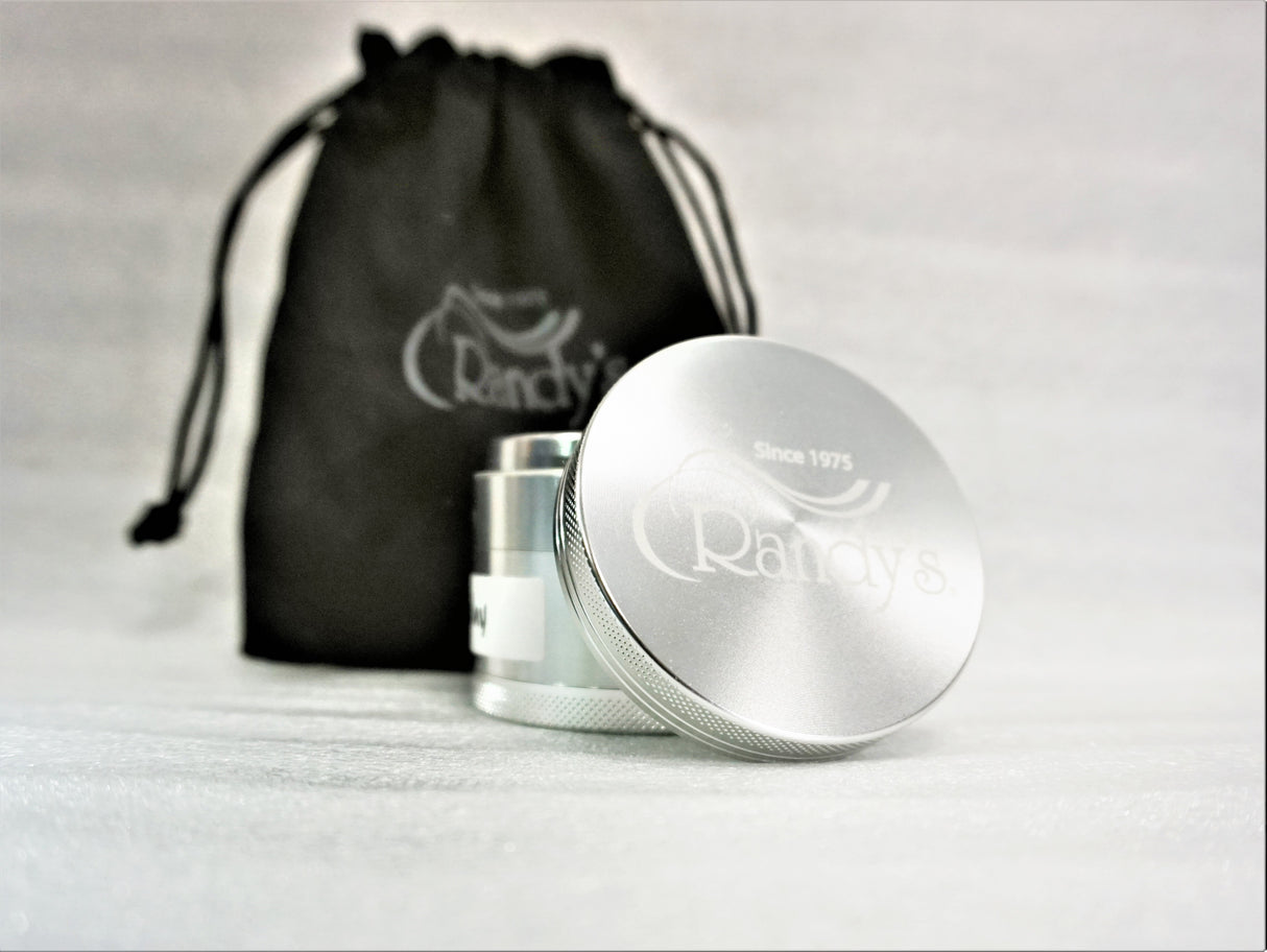 View of the Randy's 63mm Revolution Grinder in silver and its storage bag. A quality herb grinder from the Randy's brand