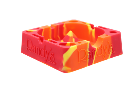 angle view of the Randy's 7" ashtray. A heat resistant and durable ash tray with storage compartments and a debowler spike in the center for ease of cleaning. casted in red yellow and orange colors