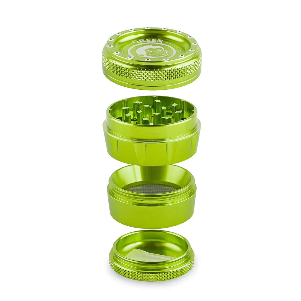Angled overhead view of the Green Monkey Tamarin 50mm grinder in green, fully disassembled to showcase its four-piece construction. This durable grinding accessory includes a magnetic top, a sharp grinding chamber, a deep flower storage catch, and a fine mesh pollen screen.