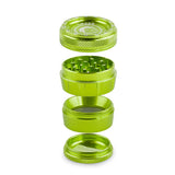 Angled overhead view of the Green Monkey Tamarin 50mm grinder in green, fully disassembled to showcase its four-piece construction. This durable grinding accessory includes a magnetic top, a sharp grinding chamber, a deep flower storage catch, and a fine mesh pollen screen.