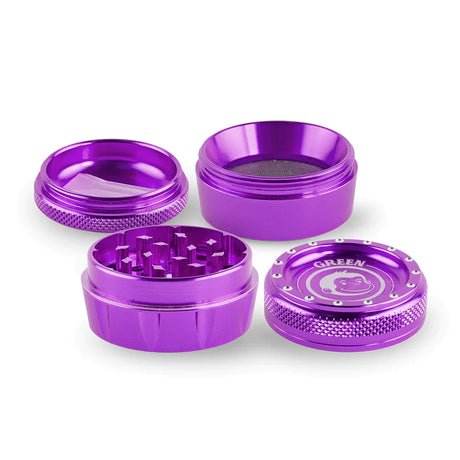 Angled overhead view of the Green Monkey Tamarin 50mm grinder in purple, fully disassembled to showcase its four-piece construction. This durable grinding accessory includes a magnetic top, a sharp grinding chamber, a deep flower storage catch, and a fine mesh pollen screen.