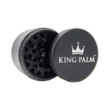 Front view of the King Palm 62mm aluminum herb grinder in sleek matte black. This premium 4-piece metal grinder features a strong magnetic lid and sharp diamond-shaped teeth to effortlessly shred dry herbs for your palm leaf rolls.