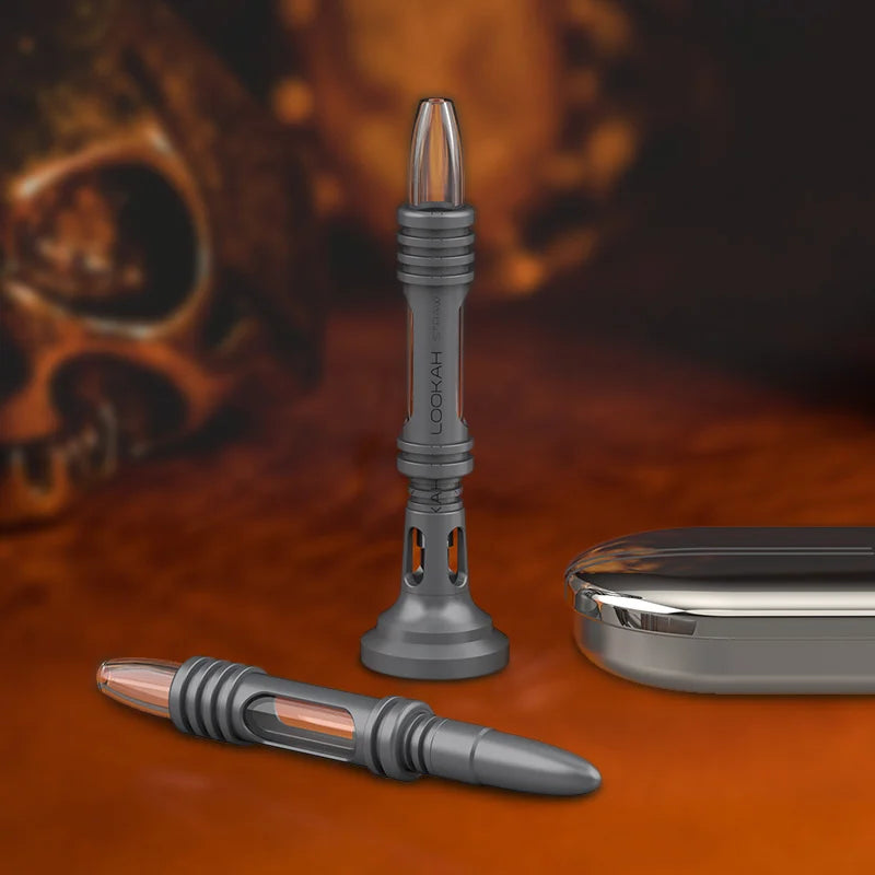 Angled front view of the gunmetal Lookah Straw nectar collector resting securely inside its included heavy desktop cooling base. This structural safety stand isolates the hot titanium tip from surfaces, allowing it to cool down safely post-session.