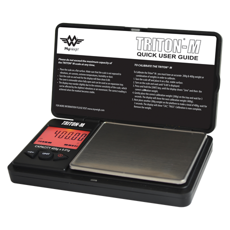 Angled overhead view of the My Weigh Triton T2 digital mini scale in black. This compact 400g x 0.01g pocket scale features a durable ribbed outer casing for precise, everyday weighing of herbs, concentrates, and small jewelry.