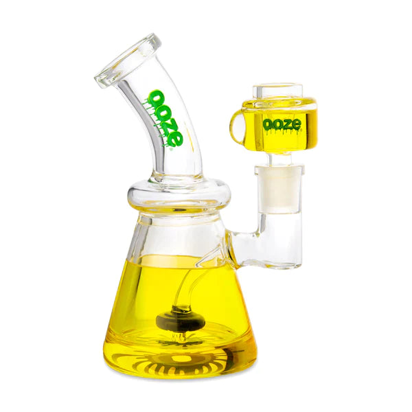 Front view of the Ooze Glyco Glycerin Freezable Water Pipe in mellow yellow. This compact 6.5-inch borosilicate glass beaker bong features a hollow base filled with bright green freezable liquid glycerin to deliver incredibly cold, ice-like hits.