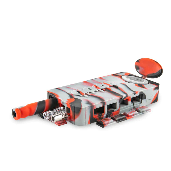 Front angled view of the Ooze Slugger Dugout Travel Kit in sleek grey black and red. This pocket-sized silicone travel piece neatly contains all your necessary concentrate accessories inside an impact-resistant, discreetly flat block.