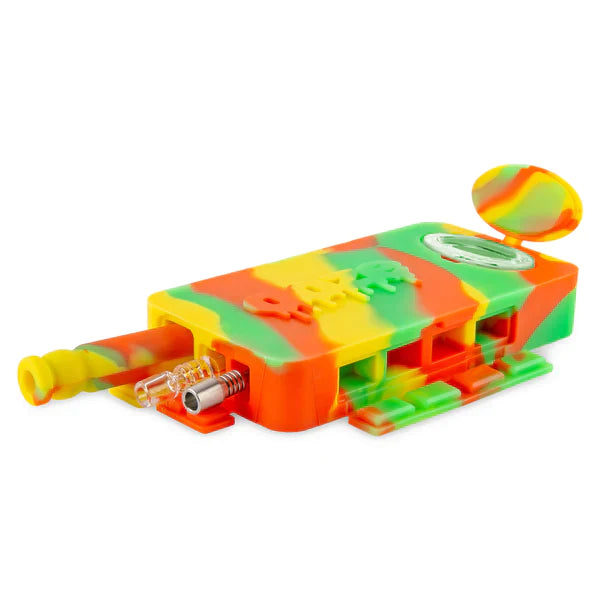 Front angled view of the Ooze Slugger Dugout Travel Kit in rasta. This pocket-sized silicone travel piece neatly contains all your necessary concentrate accessories inside an impact-resistant, discreetly flat block.
