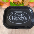 Front overhead view of the Randy's small rolling tray in classic black featuring the iconic brand logo. This compact, heavy-duty metal tray provides a smooth, flat surface to efficiently prepare and roll your dry herbs.