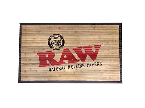 Top down view of the RAW Bamboo Floor Mat in a natural light brown wood finish with the classic red and black logo. This compact 30x18 inch door mat is perfectly suited for smaller doors to let visitors know exactly what to expect before they knock.