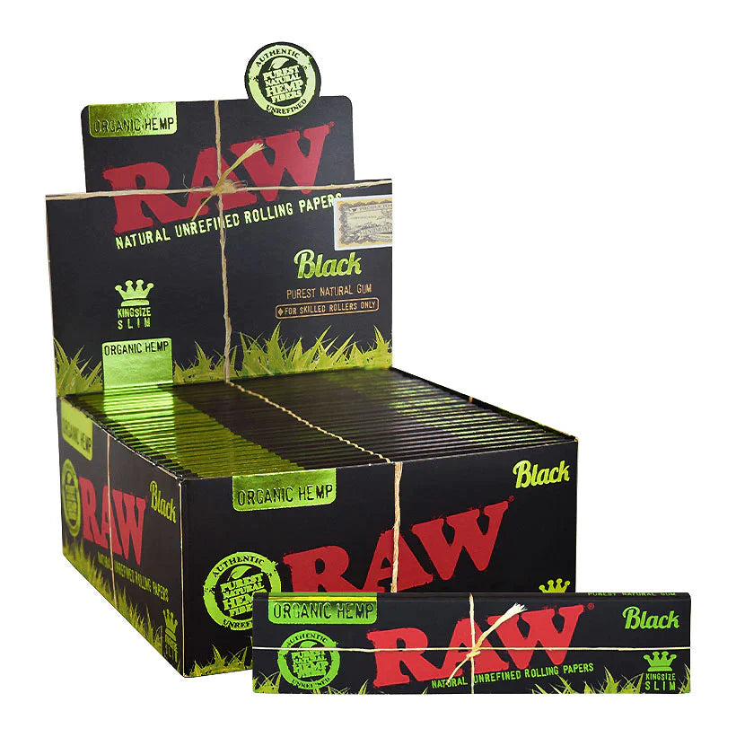Front angled view of the RAW Black Organic Hemp King Size Slim papers 50-count display box in sleek black and tan packaging with green branding. This retail-ready counter carton neatly showcases these double-pressed, ultra-thin organic hemp rolling papers for point-of-sale impulse buys.