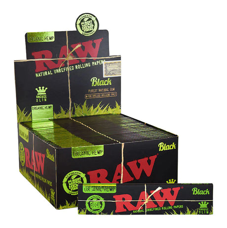 Front angled view of the RAW Black Organic Hemp King Size Slim papers 50-count display box in sleek black and tan packaging with green branding. This retail-ready counter carton neatly showcases these double-pressed, ultra-thin organic hemp rolling papers for point-of-sale impulse buys.