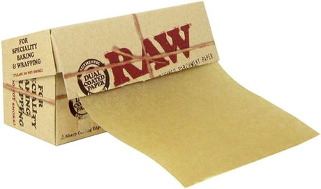 Angled overhead view of the RAW Dual Coated Parchment Paper Roll box in natural brown, shown open with the light brown parchment partially rolled out. The convenient built-in cutting edge allows extractors and dabbers to easily tear off custom lengths of non-stick paper for quick portioning.