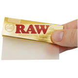 Front view of the RAW Ethereal 1 1/4 size rolling papers in a 24-count gold and black retail display box. These low-density, ultra-thin papers feature a clean tree sap adhesive and are engineered to minimize the taste of paper ash.