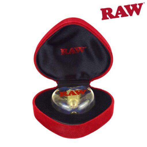 Front view of the RAW Glass Heart Cone Holder nestled inside its premium red velvet jewelry-style gift box. This limited edition borosilicate glass tip acts like a smoke stone to hold pre-rolled cones securely while adding unique style to your sessions.