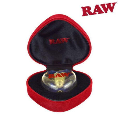 Front view of the RAW Glass Heart Cone Holder nestled inside its premium red velvet jewelry-style gift box. This limited edition borosilicate glass tip acts like a smoke stone to hold pre-rolled cones securely while adding unique style to your sessions.