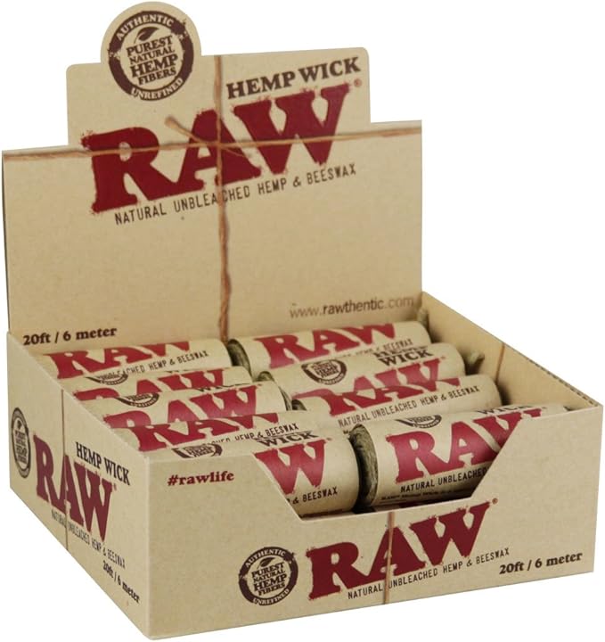 Front angled view of the RAW Hemp Wick Beeswax Coated Spool resting alongside its natural kraft brown retail box with red and black branding. This eco-friendly packaging perfectly presents the butane-free lighting tool for smoke shop retail displays and easy storage.