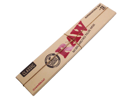Angled overhead view of the open RAW Supernatural 12-inch rolling papers booklet showing the brown and red packaging. Crafted from natural unrefined plant fibers, they feature a proprietary criss-cross watermark to ensure a slow, even burn.