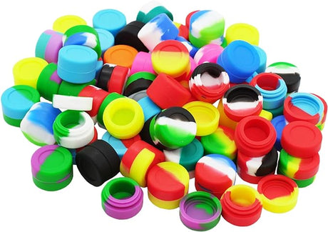 Front view of the 3ml silicone dab jars arranged in a 25-count bulk retail display box with assorted multi-color swirled patterns. These temperature-tolerant, pocket-sized containers feature a curved interior basin engineered to store and protect botanical extracts without leaving residue behind.