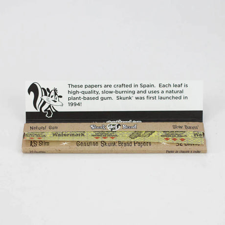 Top down view of an open Skunk Brand King Size Slim booklet revealing the ultra-thin, translucent hemp leaves. Each sheet features a shiny, plant-based vegan acacia gum line designed for a completely chemical-free, secure adhesive seal.