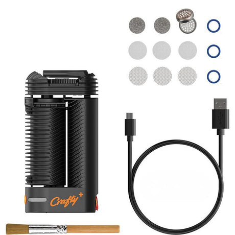 Overhead view of the Storz & Bickel Crafty+ dry herb vaporizer in matte black arranged with its original retail packaging and included accessories. The standard package includes the hybrid vape unit, replacement screens, base seal rings, a dosing capsule, a cleaning brush, and a fast-charging USB-C cable.