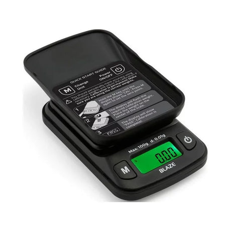 Front angled view of the Truweigh Blaze digital scale in black with its hard plastic cover detached and used as an expansion tray. Both capacity variants feature this dual-purpose lid and a tare function to easily weigh loose materials.