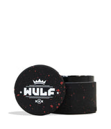 Front angled view of the Wulf 4-Piece 65mm Aerospace Aluminum Grinder in black with red splatter. Crafted from durable aerospace-grade metal, this large multi-chamber grinder effortlessly shreds dry botanicals to the perfect consistency for rolling or packing.