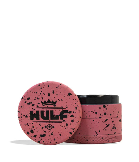Front angled view of the Wulf 4-Piece 65mm Aerospace Aluminum Grinder in pink with black splatter. Crafted from durable aerospace-grade metal, this large multi-chamber grinder effortlessly shreds dry botanicals to the perfect consistency for rolling or packing.