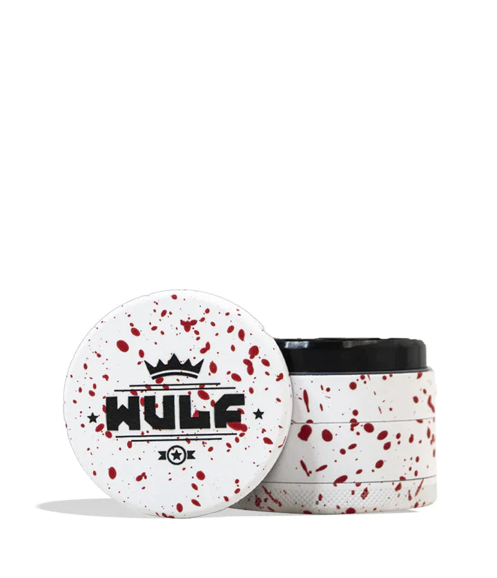 Front angled view of the Wulf 4-Piece 65mm Aerospace Aluminum Grinder in white with red splatter. Crafted from durable aerospace-grade metal, this large multi-chamber grinder effortlessly shreds dry botanicals to the perfect consistency for rolling or packing.
