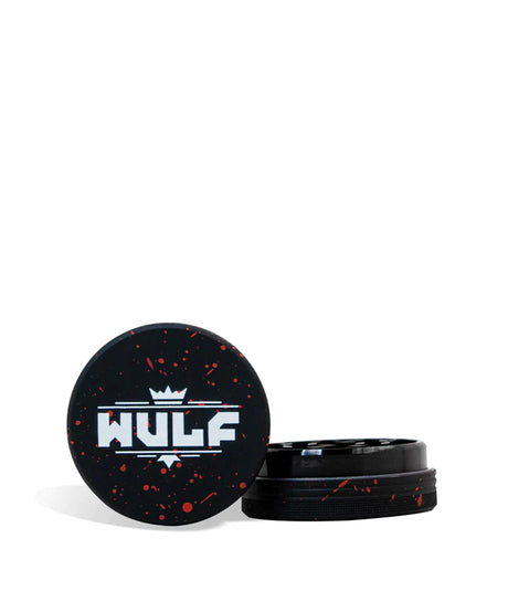 Front angled view of the Wulf Mods 2-Piece 50mm Spatter Aluminum Grinder in black with vibrant red paint splatter. This ultra-compact, travel-friendly magnetic herb grinder features a streamlined two-piece design to quickly and efficiently shred your botanical blends without any extra bulk.