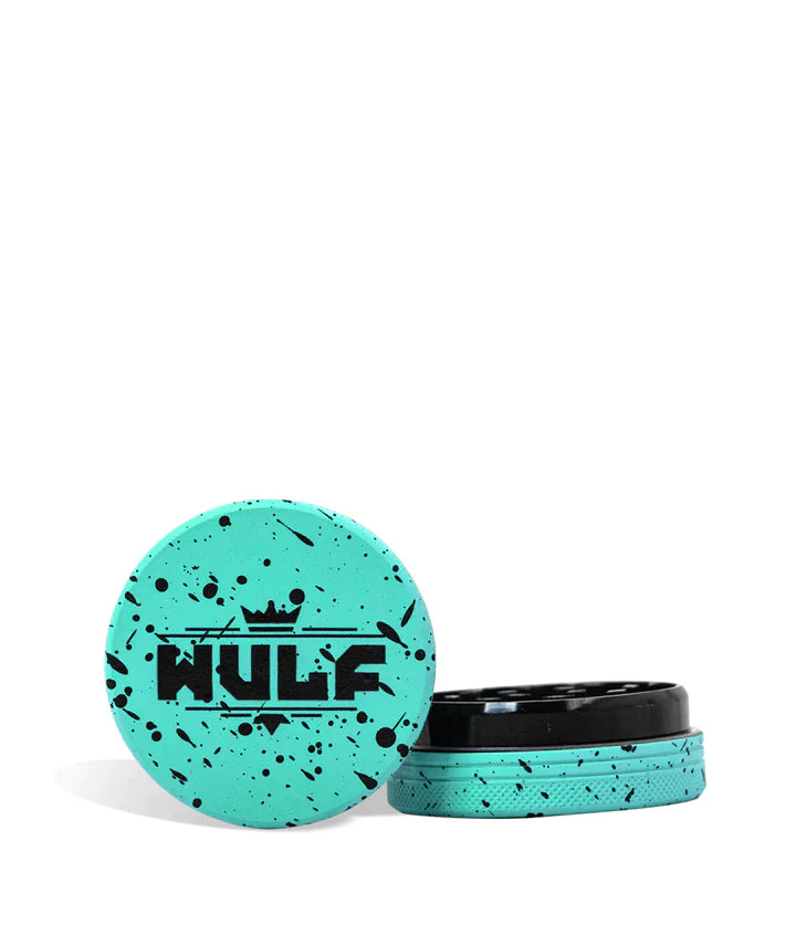 Front angled view of the Wulf Mods 2-Piece 50mm Spatter Aluminum Grinder in teal with black paint splatter. This ultra-compact, travel-friendly magnetic herb grinder features a streamlined two-piece design to quickly and efficiently shred your botanical blends without any extra bulk.