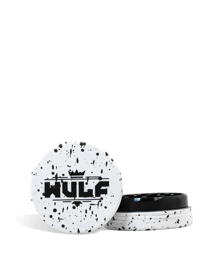Front angled view of the Wulf Mods 2-Piece 50mm Spatter Aluminum Grinder in white with black paint splatter. This ultra-compact, travel-friendly magnetic herb grinder features a streamlined two-piece design to quickly and efficiently shred your botanical blends without any extra bulk.
