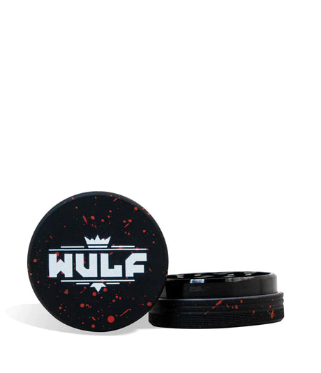 Front angled view of the Wulf Mods 2-Piece 65mm Spatter Aluminum Grinder in black with vibrant red paint splatter. This compact, travel-friendly magnetic herb grinder features a streamlined two-piece design to quickly and efficiently shred your botanical blends without added bulk.