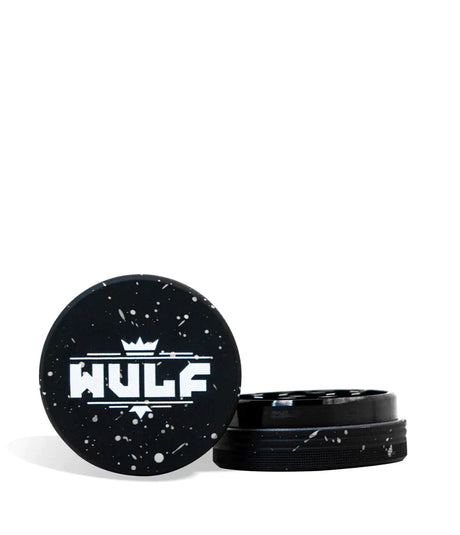 Front angled view of the Wulf Mods 2-Piece 65mm Spatter Aluminum Grinder in black with white paint splatter. This compact, travel-friendly magnetic herb grinder features a streamlined two-piece design to quickly and efficiently shred your botanical blends without added bulk.