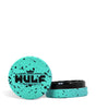 Front angled view of the Wulf Mods 2-Piece 65mm Spatter Aluminum Grinder in teal with black paint splatter. This compact, travel-friendly magnetic herb grinder features a streamlined two-piece design to quickly and efficiently shred your botanical blends without added bulk.