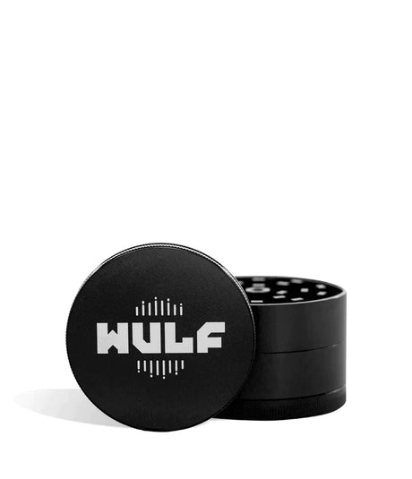 Front angled view of the Wulf Mods 4-Piece 65mm Aluminum Grinder in sleek matte black with a white logo. Crafted from heavy-duty aluminum, this multi-chamber grinder effortlessly shreds dry botanicals to the perfect fluffy consistency for rolling or packing.