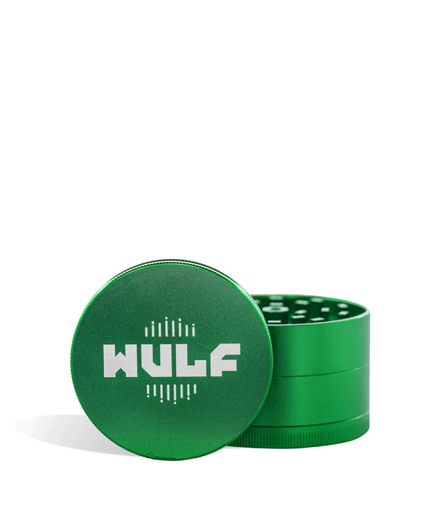 Front angled view of the Wulf Mods 4-Piece 65mm Aluminum Grinder in metallic green with a white logo. Crafted from heavy-duty aluminum, this multi-chamber grinder effortlessly shreds dry botanicals to the perfect fluffy consistency for rolling or packing.