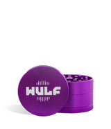 Front angled view of the Wulf Mods 4-Piece 65mm Aluminum Grinder in metallic purple with a white logo. Crafted from heavy-duty aluminum, this multi-chamber grinder effortlessly shreds dry botanicals to the perfect fluffy consistency for rolling or packing.