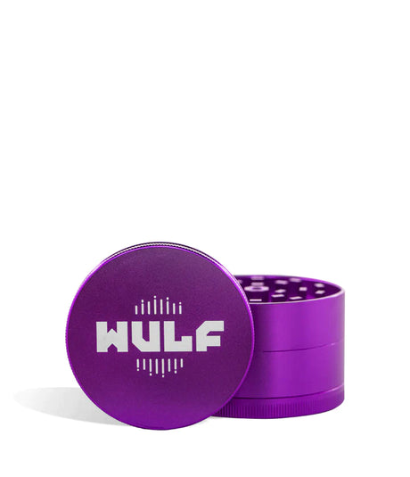 Front angled view of the Wulf Mods 4-Piece 65mm Aluminum Grinder in metallic purple with a white logo. Crafted from heavy-duty aluminum, this multi-chamber grinder effortlessly shreds dry botanicals to the perfect fluffy consistency for rolling or packing.