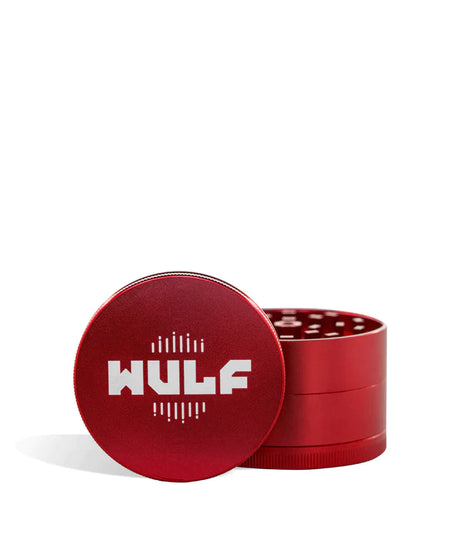 Front angled view of the Wulf Mods 4-Piece 65mm Aluminum Grinder in metallic red with a white logo. Crafted from heavy-duty aluminum, this multi-chamber grinder effortlessly shreds dry botanicals to the perfect fluffy consistency for rolling or packing.