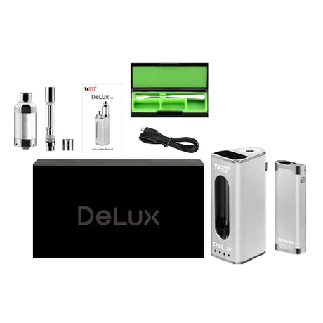 Angled overhead view of the complete Yocan DeLux 2-in-1 concentrate box mod kit laid out against a clean white background. This comprehensive dabbing starter set includes the 1500mAh main mod, 450mAh mini mod, 510-thread oil atomizer, 510-thread wax atomizer, stainless steel dab tool, and a USB charging cable.